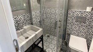Une salle de bain avec une douche à parois de verre, un lavabo et des toilettes.