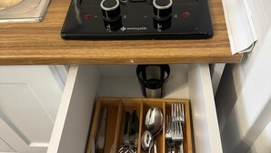 Une cuisine équipée d’une cuisinière, d’un évier et d’un tiroir contenant des ustensiles de cuisine.