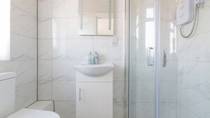 Ein modernes Badezimmer mit Toilette, Waschbecken mit Spiegel darüber und einer Duschkabine.