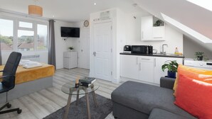 Eine moderne Wohnung mit Wohnbereich, Küchenzeile und einem Balkon mit Blick.