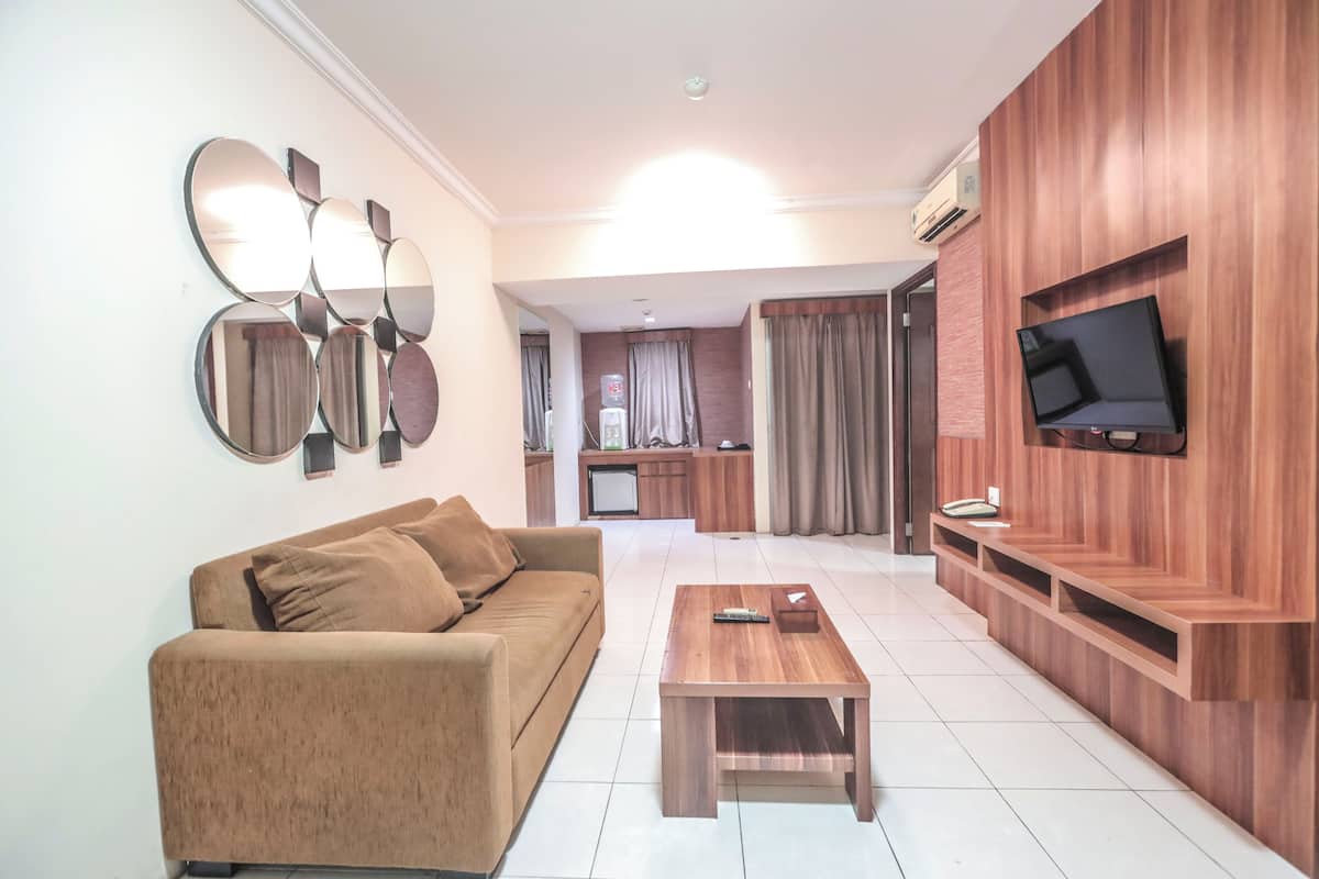 A living room with a sofa, a coffee table, and a TV mounted on a wooden wall.
