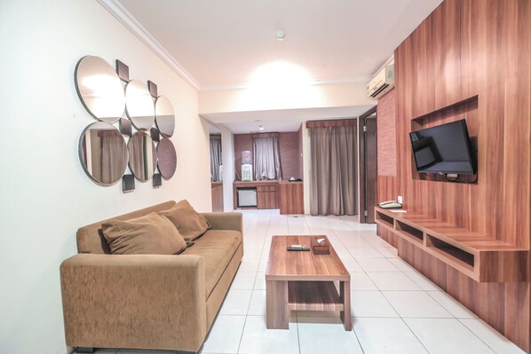 Una sala de estar con sofá, una mesa de centro y un televisor montado en una pared de madera.