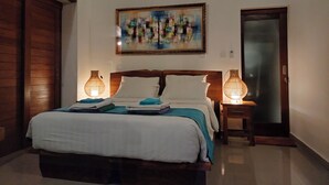 Une chambre à coucher avec un lit en bois, deux lampes de chevet, un tableau au mur et une porte en verre dépoli.