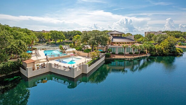 Un resort con una piscina central, un área de piscina separada y un edificio de techo plano.