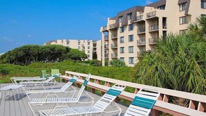 Un resort con zona de piscina, tumbonas y terraza de madera.