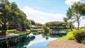 A serene landscape with a calm water body, lush greenery, and a bridge. - Spacious 2BR Condo | Balcony + Resort Amenities (Hilton Head Island)