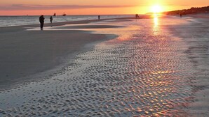 A beach at sunset with people walking along the shore. - Spacious 2BR Condo | Balcony + Resort Amenities (Hilton Head Island)