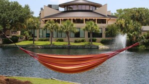 A hammock over a body of water with a building in the background.