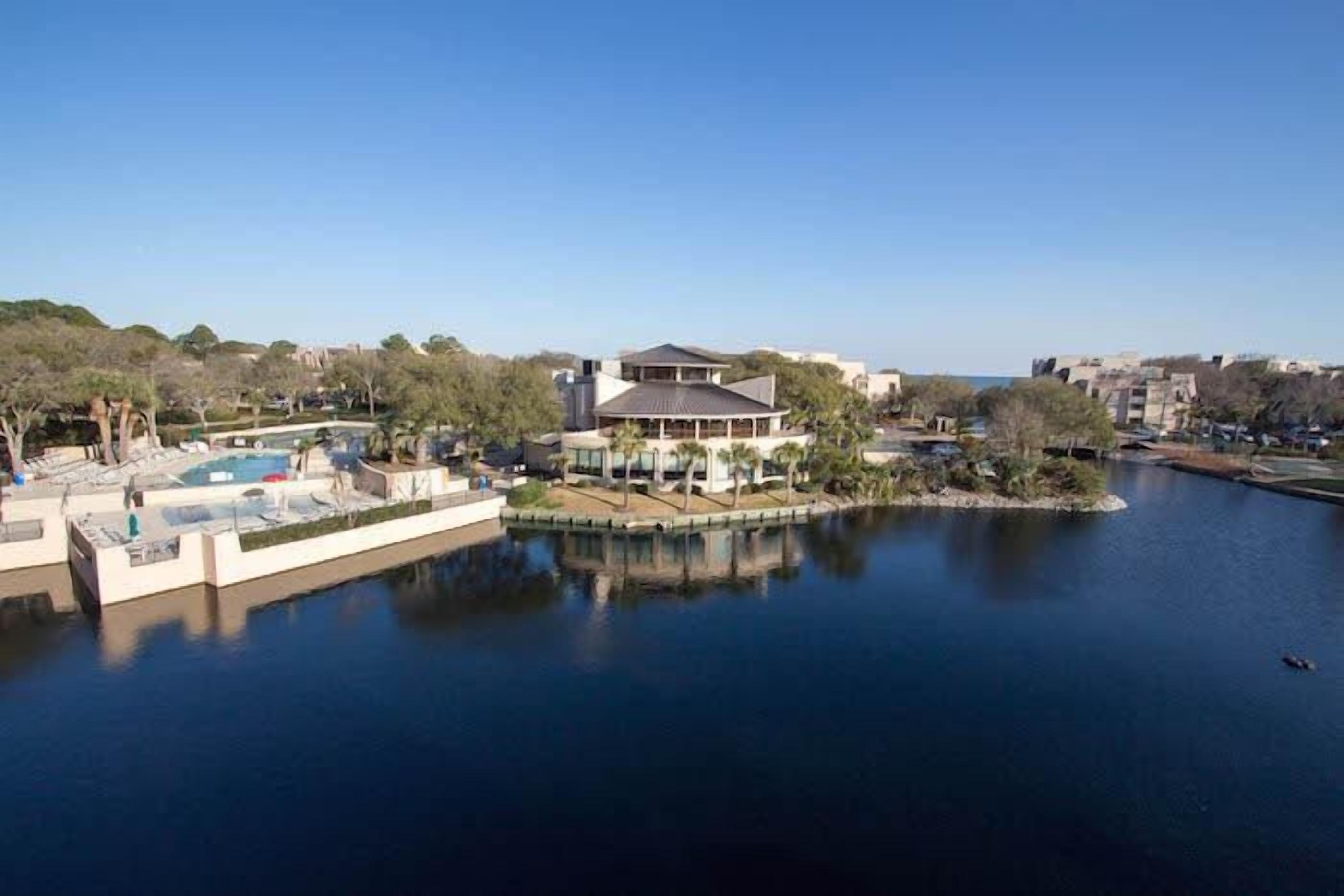 A waterfront property with a large house, a swimming pool, and a dock.