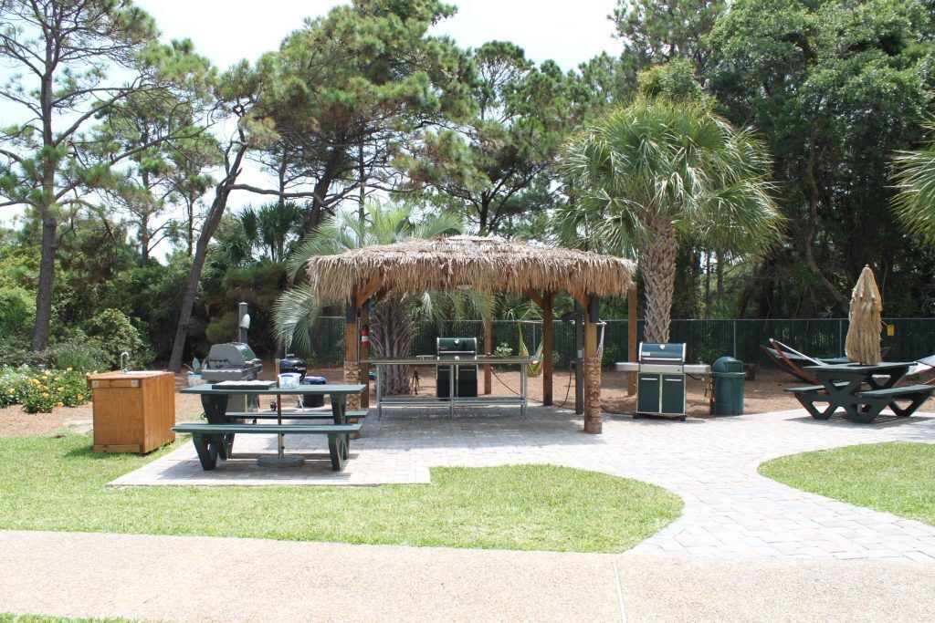 An outdoor patio area with picnic tables, a barbecue grill, and a covered seating area.