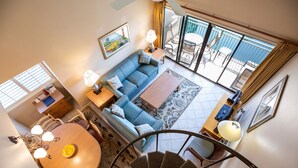 A spacious living area with a sofa, dining table, and a staircase leading to a balcony.