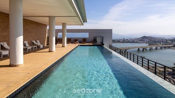 A modern infinity pool with a view of a city and mountains. - TVT - Luxury Studios in the Center of Florianopolis (Florianópolis)