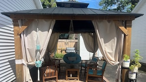 A covered outdoor seating area with wooden furniture and potted plants. - Cozy Vibe, Clean, Beach Access, 10 mins to GOTL! (Ashtabula)