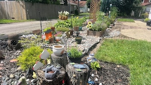 A garden with various decorative items, including a wooden fence, potted plants, and a bird feeder. - Cozy Vibe, Clean, Beach Access, 10 mins to GOTL! (Ashtabula)