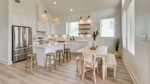 Una cocina moderna con armarios blancos, electrodomésticos de acero inoxidable y una isla central con taburetes.