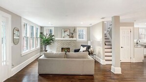 A spacious living room with a fireplace, a sofa, and a staircase leading to another area. - Springfield Charmer Clean, Spacious,  with WI-FI Close to all! (Jacksonville)