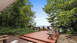 A wooden deck with outdoor seating and a view of the sea. - Cottage with Private Lake Access! Short distance to town (West Olive)