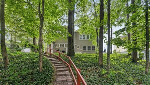 A stone staircase with red railings leading up to a house surrounded by lush greenery. - Cottage with Private Lake Access! Short distance to town (West Olive)