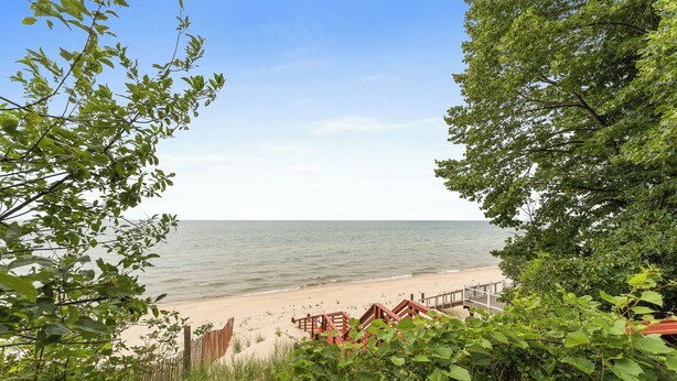 A beach with a wooden walkway leading to a sandy area, surrounded by greenery. - Cottage with Private Lake Access! Short distance to town (West Olive)