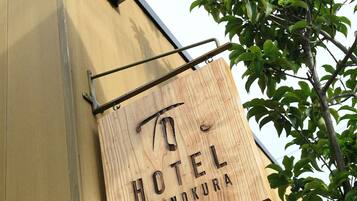 A wooden sign with "HOTEL ISHINOKURA" written on it, mounted on a building.
