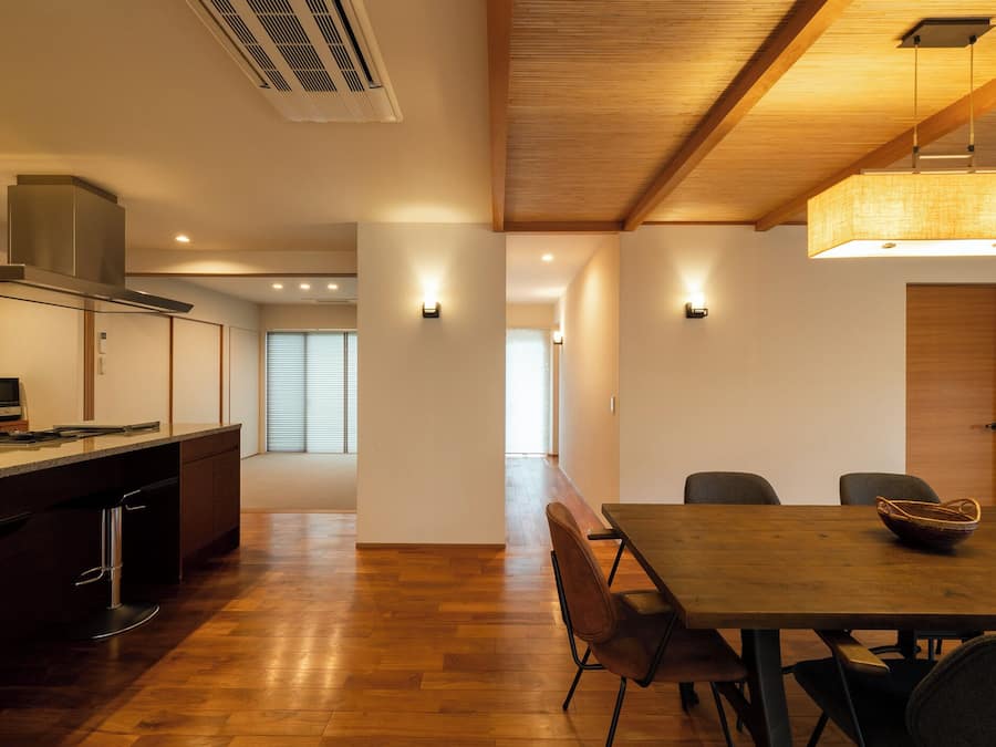 Una cocina moderna con una isla central, suelo de madera y una zona de comedor con mesa y sillas.