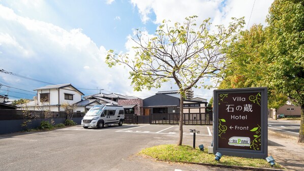 A parking area with a sign for Villa Hotel, a parked van, and a tree. - Villa Ishinokura Hotel (Saga)