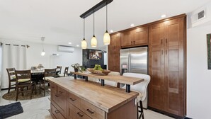 A modern kitchen with wooden cabinets, a central island, pendant lights, and a built-in refrigerator. - Spacious 4-bedroom house with WiFi and AC in fantastic Chandler (Chandler)