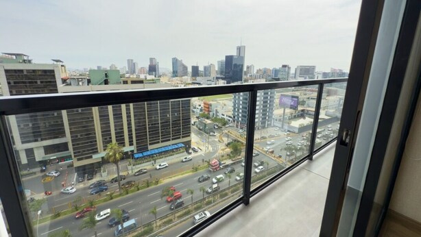 A high-rise building with a view of a cityscape, including modern skyscrapers and a busy road with vehicles.