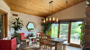 A cozy dining area with a wooden table and chairs, surrounded by potted plants and a large window offering a view of the outdoors. - Spacious 4-bedroom house with private Sauna, Hot tub, Fitness room in Big Sky (Big Sky)