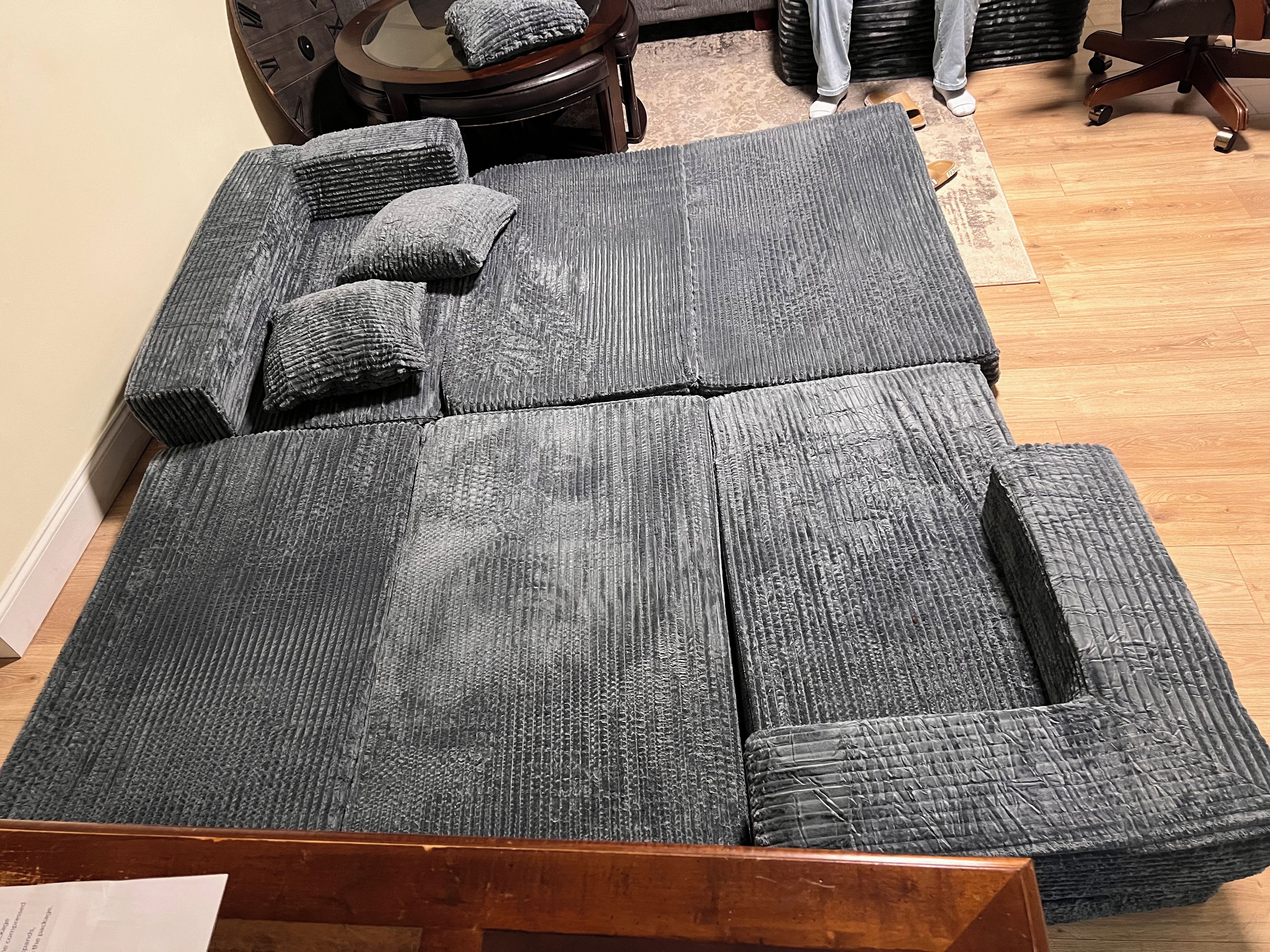 Una habitación con un amplio sofá modular, una mesa de centro de madera y una pequeña mesa redonda con sillas.