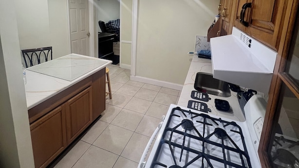 A compact kitchen with a gas stove, wooden cabinets, and a small dining area.