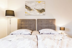 A double bed with a headboard, a bedside lamp, and a wall-mounted abstract painting.