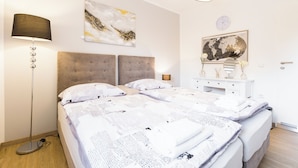 A bedroom with a large bed, two bedside tables, a floor lamp, and artwork on the walls.