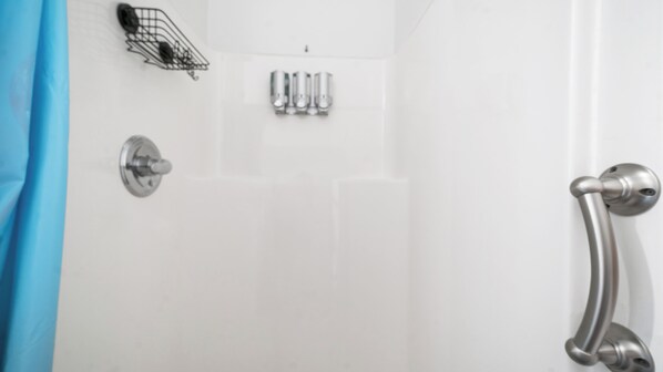 A bathroom with a shower, a handrail, and a towel rack with multiple towels.