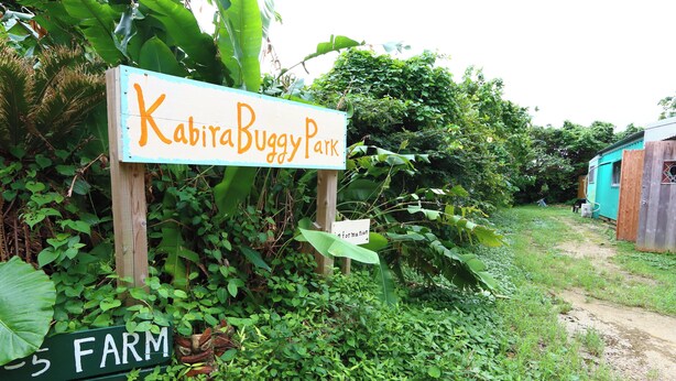 Un panneau indiquant le «parc Kabita Duggy», entouré d’une végétation luxuriante et bordé d’un sentier de terre.