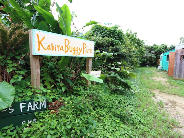 A sign for 'KABITA Duggy Park' surrounded by lush greenery and a dirt path. - Yadoya Lotus (Ishigaki)