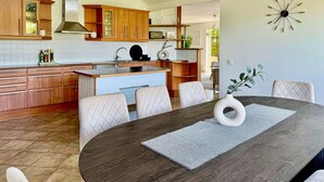 Une cuisine moderne avec des meubles en bois, un îlot central et un coin repas comprenant une table ronde et des chaises.