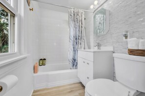 A bathroom with a bathtub, toilet, vanity, and a window. - Entire Private Apartment w/Patio and Big Driveway. (New Haven)