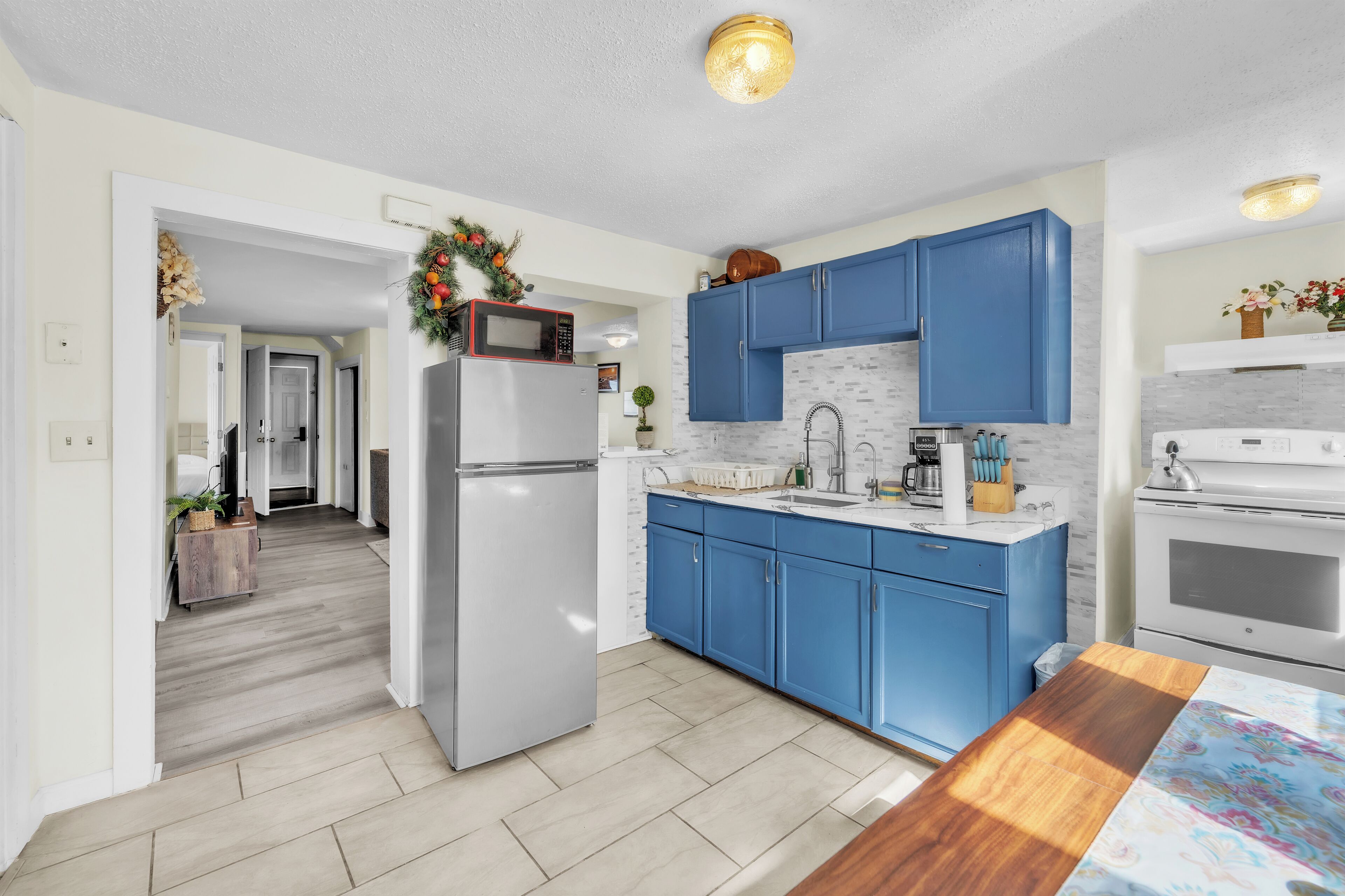 A modern kitchen with blue cabinets, a stainless steel refrigerator, and a white stove.