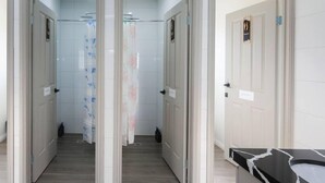 En moderne hotellobby med en central gang der fører til værelser, hvert med en dør og et lille vindue.