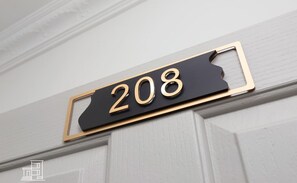Une plaque indiquant le numéro de maison, portant le numéro 208.