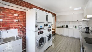 A laundry room with a washing machine and dryer, a sink, and a countertop with a kettle.