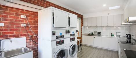 A laundry room with a washing machine and dryer, a sink, and a countertop with a kettle.