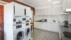 A laundry room with a washing machine and dryer, a sink, and a countertop with a kettle.