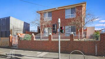 A two-story brick building with a white fence, a traffic light, and a pedestrian crossing.