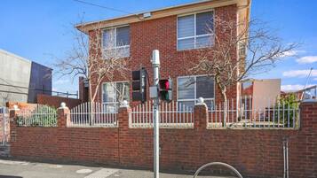 A two-story brick building with a white fence, a traffic light, and a pedestrian crossing.
