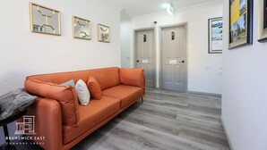 Eine moderne Lobby mit einer Ledersofa, Spiegeln in Rahmen und einer Treppe zu einer Tür.