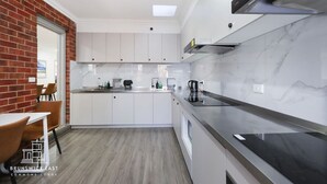 Eine moderne Küche mit weißen Schränken, einer schwarzen Arbeitsplatte und einer Wand aus Backsteinen.