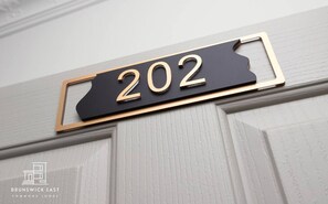 Una targa con il numero 202 su una porta bianca.