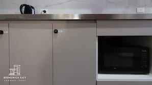 Une cuisine équipée d’un four à micro-ondes, de placards et d’une bouilloire.